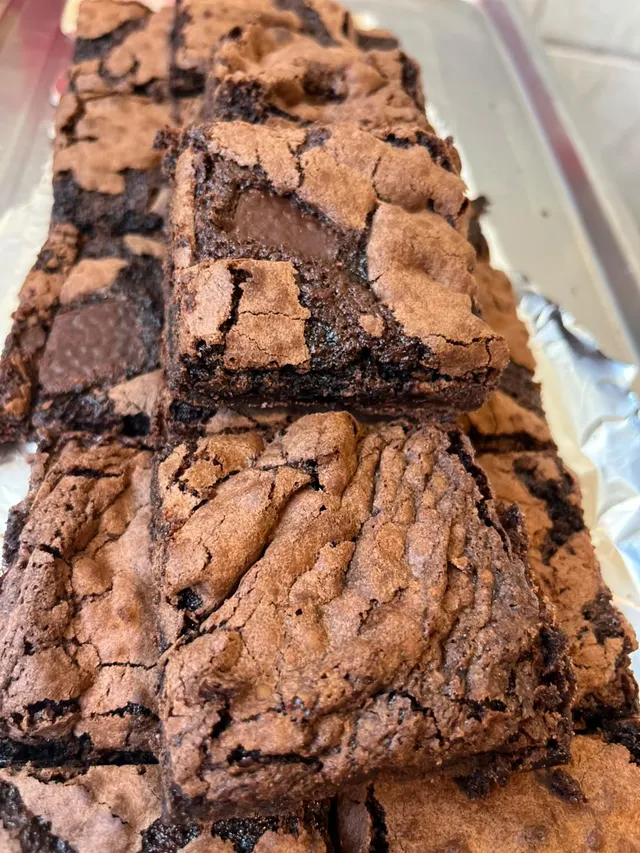 Pedaços de brownie empilhados mostrando a casquinha craquelada e o chocolate por dentro