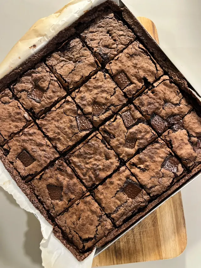 Forma de brownie com pedaços de chocolate, sobre tábua de madeira